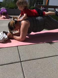 une femme faisant du yoga avec un enfant sur son dos 